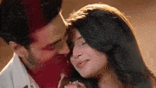 a man and a woman are kissing each other on the forehead .
