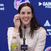 a woman is sitting in front of a microphone with a bottle of gatorade in front of her .