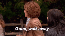 a woman in a brown jacket is holding a glass of wine and says `` good , walk away '' .