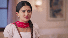 a woman wearing a white shirt and a red scarf is making a face