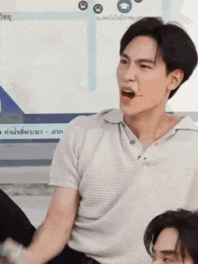 a man in a white shirt is making a funny face while sitting in front of a screen .