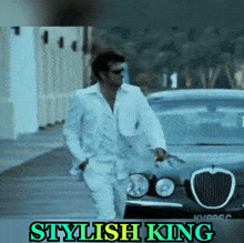 a man in a white suit is standing in front of a car with the words stylish king on the bottom