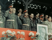 a group of men in military uniforms salute in front of a picture
