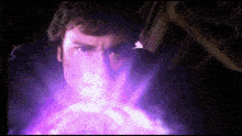 a close up of a man 's face with a purple light coming out of his mouth .