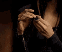 a woman is holding a rosary in her hand and looking at it .