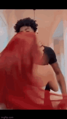 a man is covering his face with a red cloth while a woman is standing next to him .