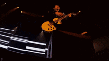 a man is playing a guitar in a dark room with the letter d in the corner
