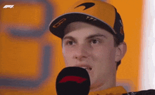 a man wearing a mclaren hat speaks into a microphone