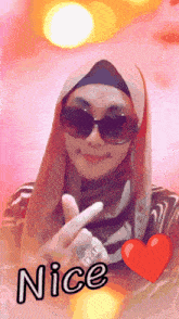 a woman wearing a hijab and sunglasses is giving a peace sign with the word nice below her