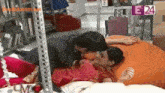 a man kissing a woman on a bed with e24 on the bottom right corner
