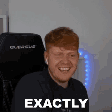 a man is sitting in a chair and smiling with the words `` exactly '' on his face .