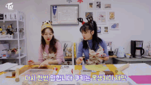 two girls are sitting at a table with korean writing on it