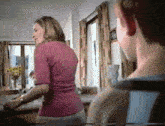 a woman in a pink shirt is standing next to a man in a living room