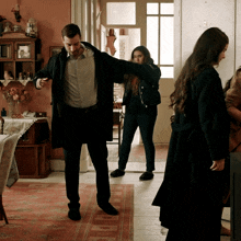 a man in a black coat stands in a living room