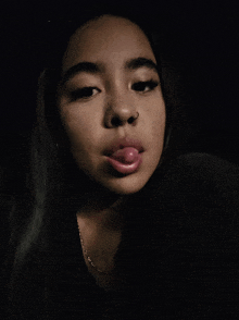 a woman sticking her tongue out and wearing a necklace