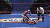 two wrestlers are wrestling in a ring with a cmc logo on the floor
