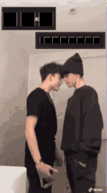 two young men are standing next to each other and looking at each other in front of a sign that says " tiktok "
