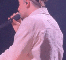 a man in a white shirt is singing into a microphone on stage .