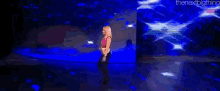 a woman is standing on a stage in front of a large screen .