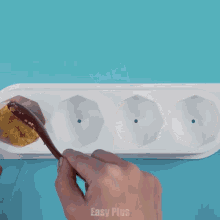 a person is using a wooden spoon to scoop food out of a tray