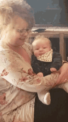 a woman is holding a baby in her arms and the baby has a bib on