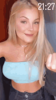 a woman wearing a blue crop top and jeans is giving the middle finger .