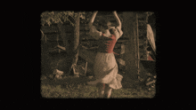 a woman in a red and white dress is dancing in front of a tree