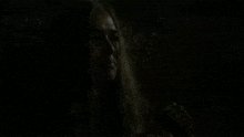 a woman is crying in a dark room while looking up .