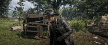 a man in a leather jacket and top hat is smoking a cigarette in a field .