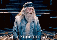 a man with a beard and a hat is standing in a room with the words accepting defeat .