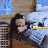 a young boy is laying on a bed with a blanket and a toy in his hand