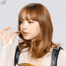a woman with red hair is eating a piece of food from a box .
