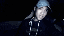 a man wearing a baseball cap and earbuds is looking at something in the dark .
