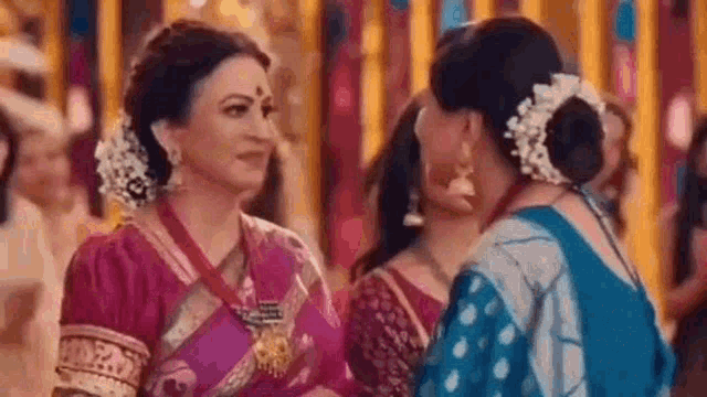 a group of women are standing next to each other in a room talking to each other .
