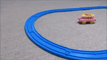a blue toy train is going down a track