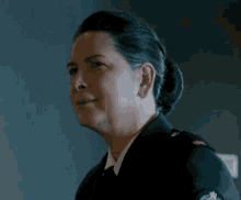 a woman in a military uniform is smiling and looking away from the camera .
