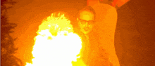 a man wearing glasses stands in front of a fire