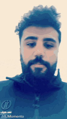 a man with a beard wearing a momento jacket looks at the camera