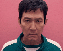 a man wearing a green and white jacket is looking at the camera .