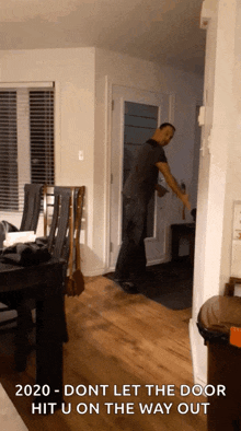 a man is standing in a living room with the words 2020 dont let the door hit u on the way out