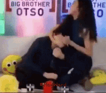 a woman is hugging a man in front of a big brother otso sign