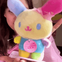 a woman is holding a stuffed bunny with a tag that says " happy day "