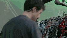 a man in a black shirt is working on a mixer with a lot of wires coming out of it