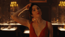 a woman in a red dress holds her hand to her head in a dark room