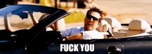 a man is driving a convertible car with the words `` fuck you '' written on the bottom .