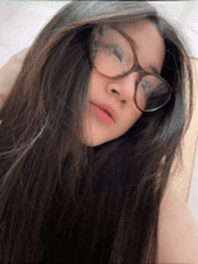 a girl with long hair wearing glasses is taking a selfie .