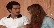 a man and a woman are sitting next to each other and looking at each other .