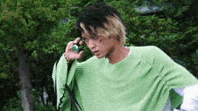 a man in a green sweater is talking on a phone