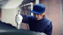 a woman wearing a blue hat is working on a vehicle