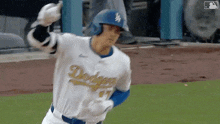 a baseball player wearing a dodgers uniform and helmet is running on the field .